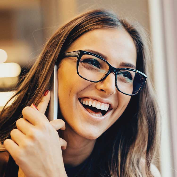 Smiling woman talking on the phone while wearing glasses